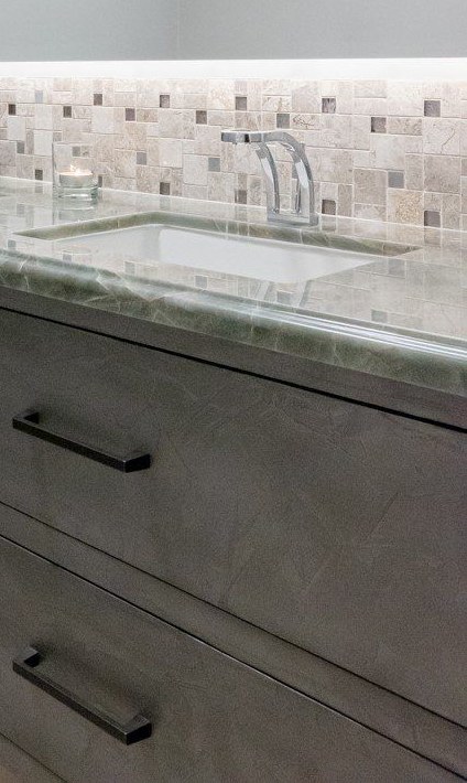 Powder room with a green marble vanity top and a stone mosaic backsplash